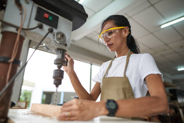 istock Young woman carpenter drills on wood 1256317506