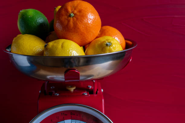 Citrus fruit in red vintage kitchen scales Oranges, lemons and limes In a red retro weighing scale vintage kitchen scale with fruit stock pictures, royalty-free photos & images