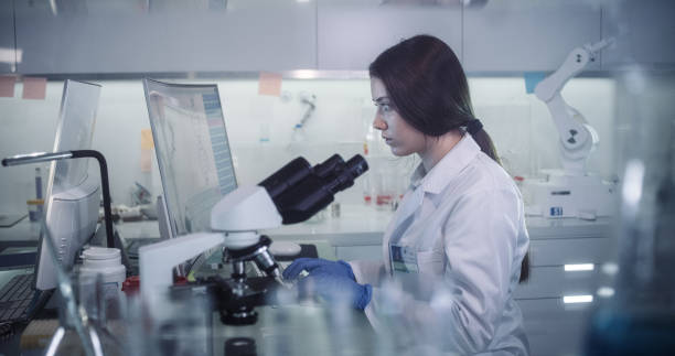 istock Female scientists working in futuristic laboratory. Looking through glassware 1256322567