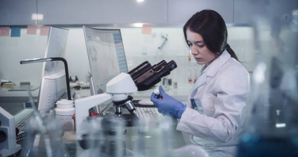 istock Female scientists working in futuristic laboratory. Looking through glassware 1256322611