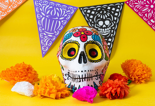 Hand painted skull, colorful day of the dead banner and colorful flowers on yellow background. Day of the dead altar