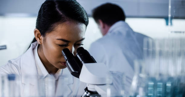 istock Multi ethnic team working in futuristic laboratory. Looking through glassware 1256322823
