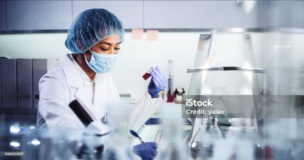 Asian female doctor working with pathogen samples. Using microscope Young woman during virus lab tests Laboratory Stock Photo
