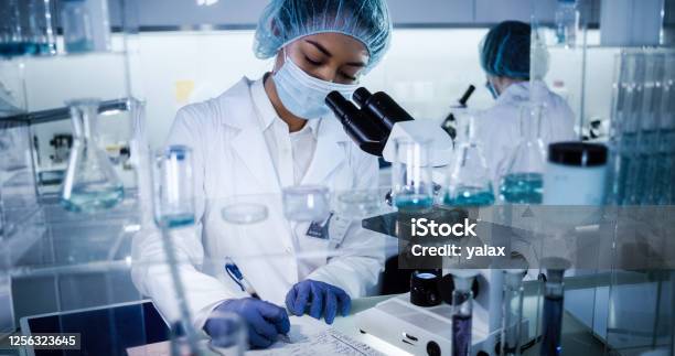 Multi Ethnic Female Team Studying Dna Mutations Using Microscope In Protective Workwear Stock Photo - Download Image Now