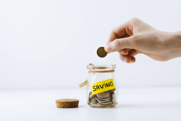istock Female hand puts a coin in a jar. 1256331062