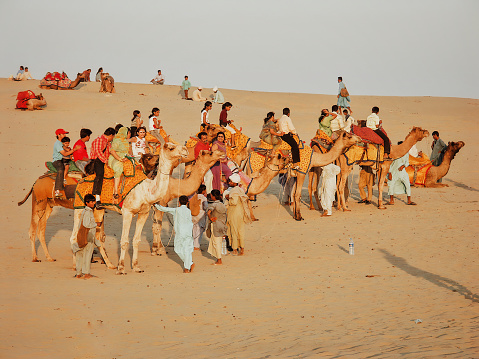 Sam Dunes, Rajasthan, India - November 23, 2004: a large group of Indian tourists     , men,women and children, sitting on a camel, are enjoying a camel ride in the sand dunes near Jaisalmer.