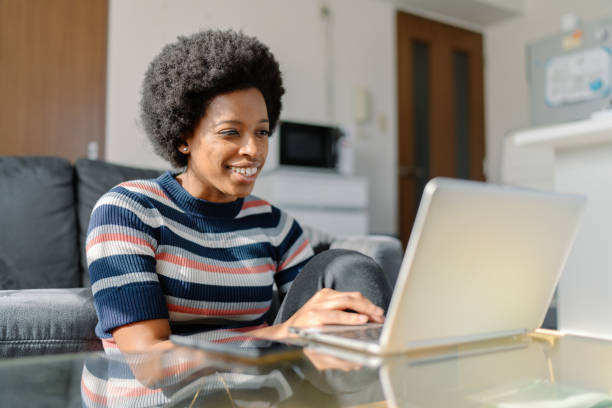 istock Young Black woman using laptop at home 1256333378