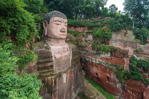 Leshan, China - July 2019 : The close up of the head and torso of the Giant Leshan Buddha, a 71-meter tall stone statue built between 713 and 803 during the Tang Dynasty. Located at the confluence of the Minjiang, Dadu and Qingyi rivers in the southern part of Sichuan province