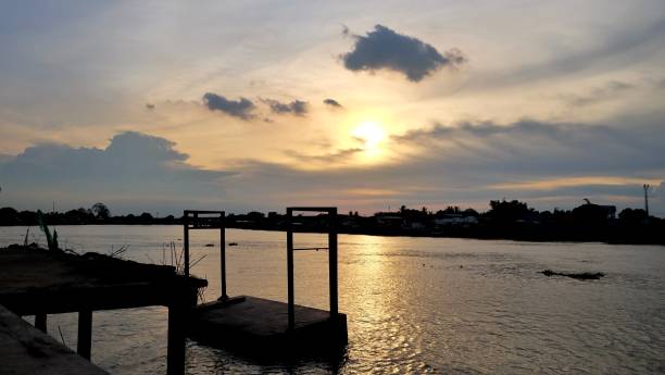 istock Silhouette sunset over Chaopraya river with dark clouds sky at dusk and  blurred cement pathwat beside a river,a point view 1256334410