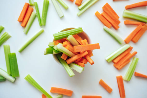 in scheiben geschnittene karotten und sellerie in einer weißen schüssel, gesundes essen, rezept hintergrund - celery stock-fotos und bilder