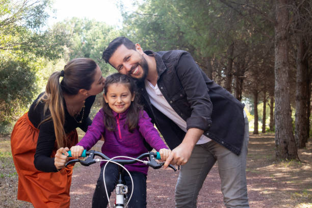 istock Parents teaching daughter how to ride a bicycle at park 1256338586