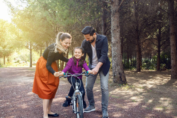 istock Parents teaching daughter how to ride a bicycle at park 1256338817