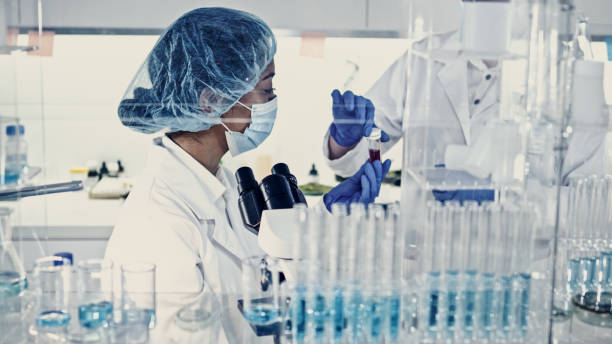 istock Female team working in futuristic laboratory. Looking through glassware 1256339258