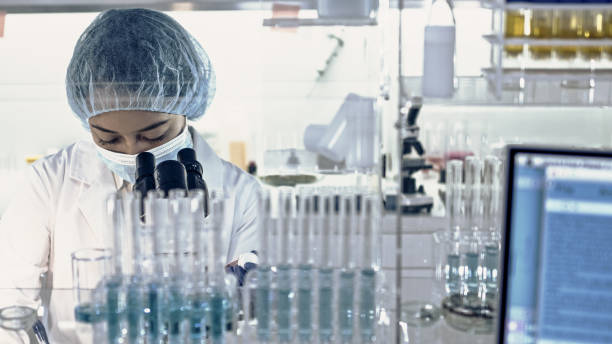 istock Female team working in futuristic laboratory. Looking through glassware 1256339271