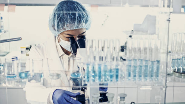 istock Female team working in futuristic laboratory. Looking through glassware 1256339285