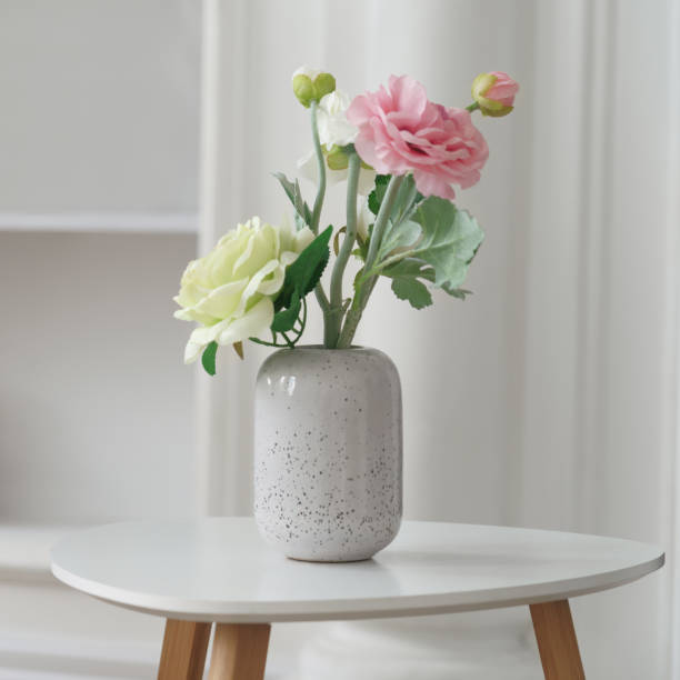 istock Pink and yellow roses in Modern white vase on white side table 1256341473
