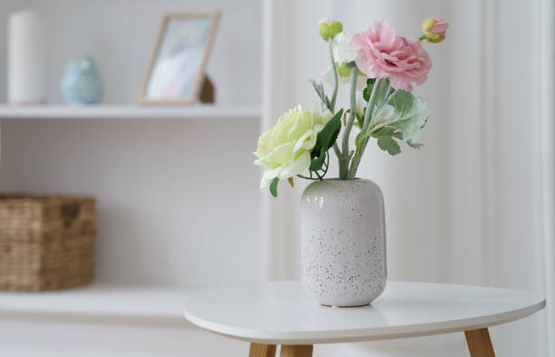 istock Pink and yellow roses in Modern white vase on white side table with copy space 1256341780
