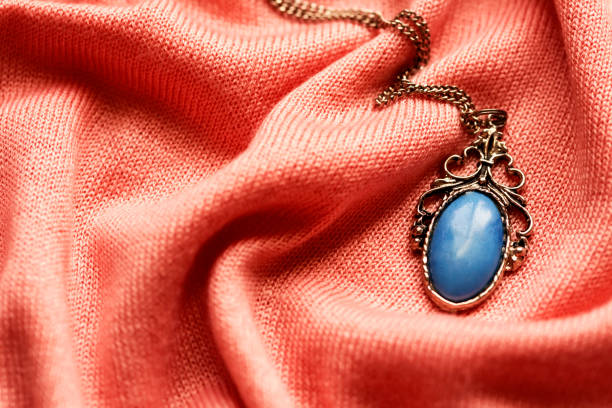 istock old antique medallion with blue gemstone on a soft pink fabric background 1256345463