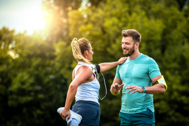 casal feliz fazendo exercícios de alongamento no parque - couple stretching running jogging - fotografias e filmes do acervo