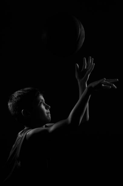 istock Side View Of Boy Playing With Ball Against Black Background 1256347187