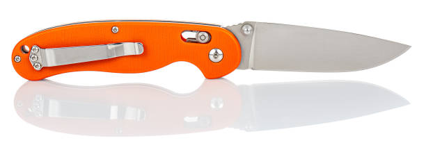 Side view of open folding pocket knife with matte blade and orange composite plastic cover plates on steel handle isolated on white background with reflection on glossy surface. Pocket knife close-up vista lateral del cuchillo de bolsillo plegable abierto con cuchilla mate y placas de cubierta de plástico compuesto naranja sobre mango de acero aislado sobre fondo blanco con reflejo sobre superficie brillante. cuchillo de bolsillo de cerca