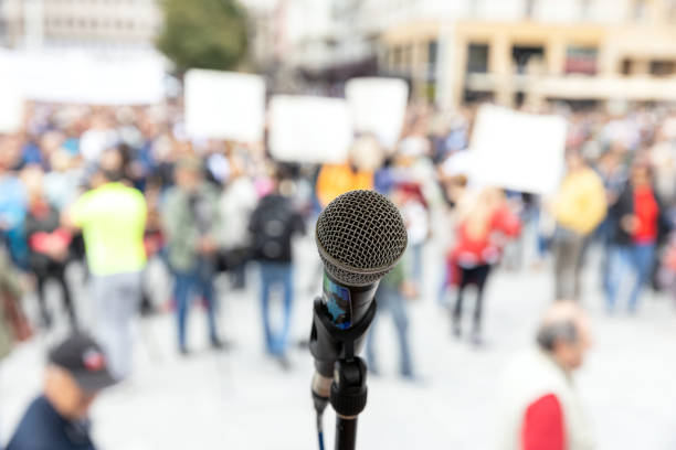 istock Social protest or public demonstration. Microphone in focus against unrecognizable crowd of people. 1256348403