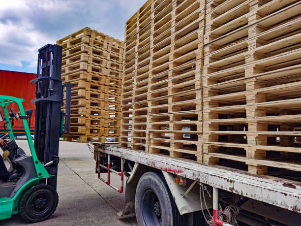 istock Worker driving forklift to loading and unloading wooden pallets from truck to warehouse cargo storage, shipment in logistics and transportation industrial, wood pallets stack 1256349229