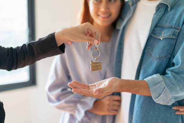 jeune couple asiatique recevant la clé d’appartement ou de chambre neuve de l’agent immobilier ou agent de vente d’immobiliers après avoir fini un contrat de location ou d’achat. - real estate investment real estate agent real estate office photos et images de collection