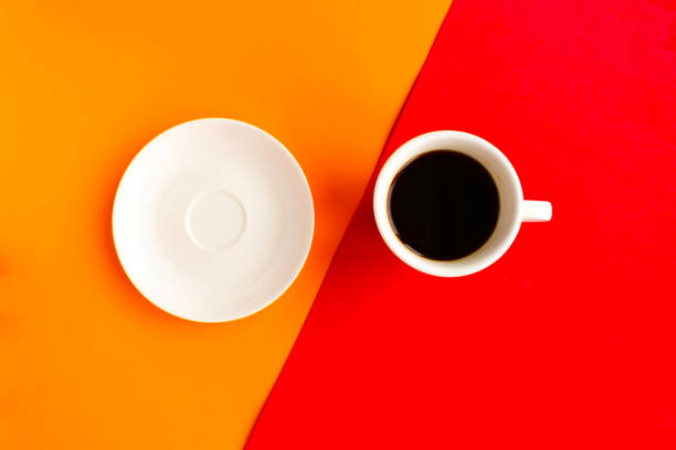 istock Empty plate and coffee cup on geometric orange and red background, top view. Minimal concept 1256354957