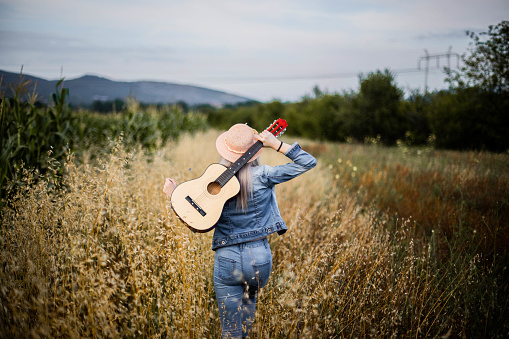 Vista trasera de la chica con guitarra en el campo photo