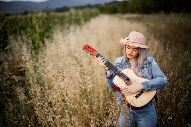 istock One beautiful young women is playing guitar at field 1256355792
