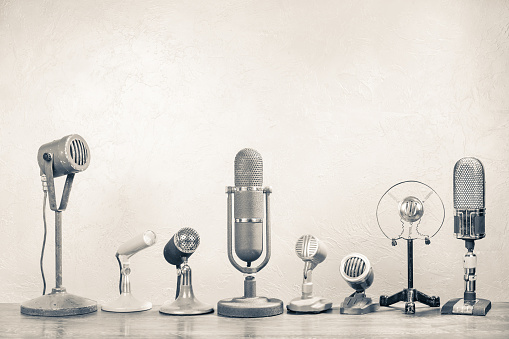 Retro microphones for press conference or interview on wooden table. Vintage old style sepia photo
