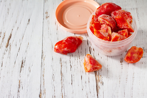 Healthy food is frozen food for the winter. Containers with frozen tomatoes. Copy space.