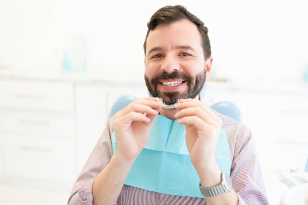 Patient With Invisible Aligner At Clinic Portrait of smiling Caucasian mid adult man holding clear orthodontic retainer dental aligner photos stock pictures, royalty-free photos & images