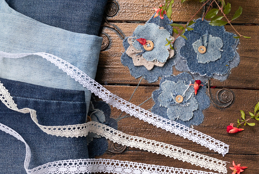 Flowers from old jeans decoration of the box on selective focuse background with pommegranate flowers and redy to recycling jeans. Concept of things reuse and natural resources preserving.