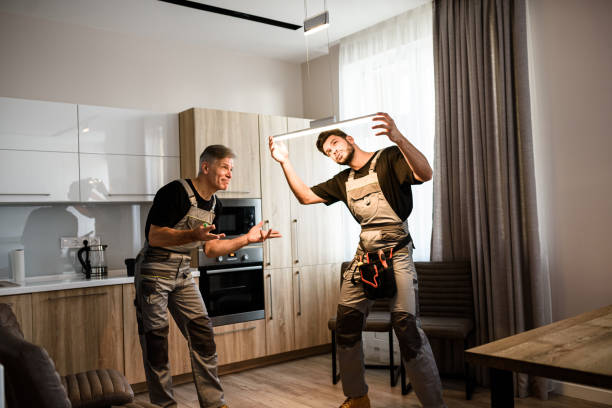 istock Done. Two electricians, workers in uniform finished fixing or installing electric lamp, light inside apartment in the kitchen. Construction decoration concept 1256368331