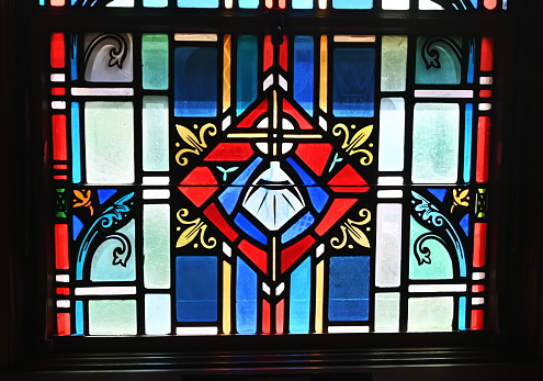 Stained glass shell with water and cross in church.