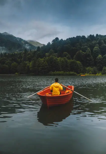 Photo of A man rowing in a boat enjoying the early morning over the Black Lake, Borçka ,Artvin, Turkey