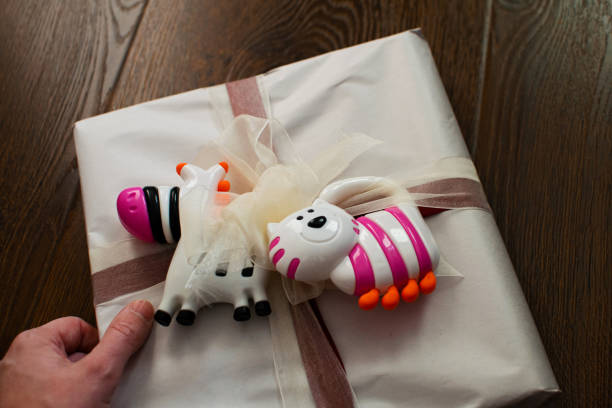 gift tied with a bow for a newborn with rattles. gift for newborn, birthday. rattles for baby. - baby congratulating toy birthday imagens e fotografias de stock