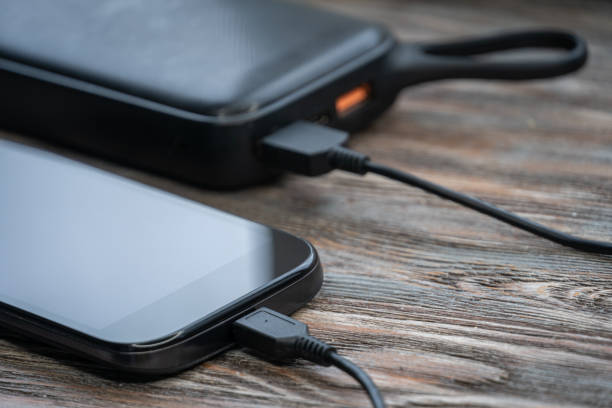 istock Smartphone charging with black power bank on wood background 1256378068