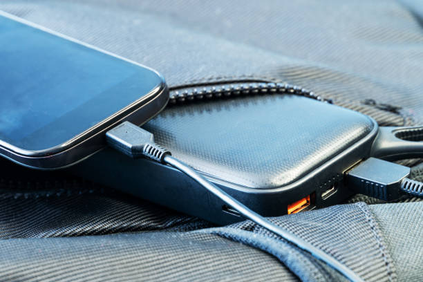 istock Smartphone charging with black energy bank in backpack 1256378103