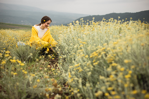 Woman is sitting in herb field and enjoying nature