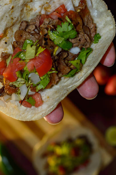 istock Tijuana tacos, holding grilled carne asada taco 1256379307