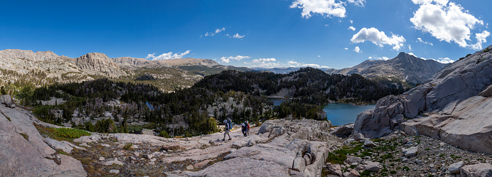 Three male backpackers ascend a rock face on the northeast side of Douglas Peak in the Wind River Mountain Range in Wyoming. Panoramic compilation.