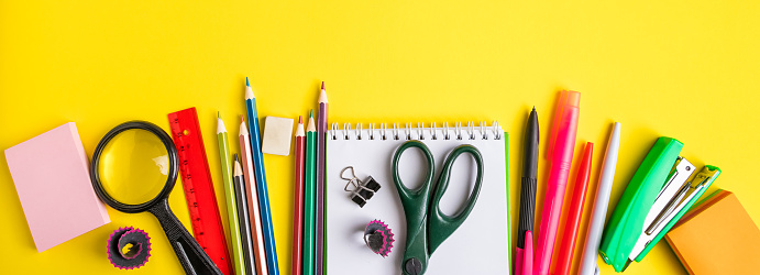 Back to school concept. Flat lay of office supplies on a yellow background. Place for text. Banner format