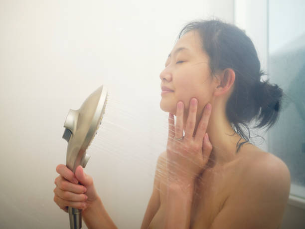 A young Japanese woman relaxing in a warm shower.