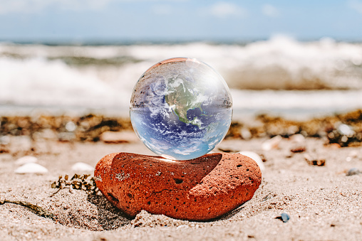Crystal ball reflecting globe of the earth in beach \nhttps://www.nasa.gov/sites/default/files/1-bluemarble_west.jpg