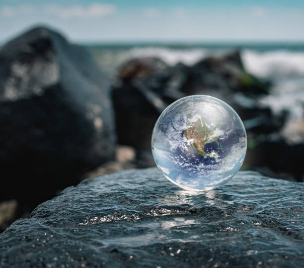 istock Crystal ball reflecting globe of the earth in beach 1256388820