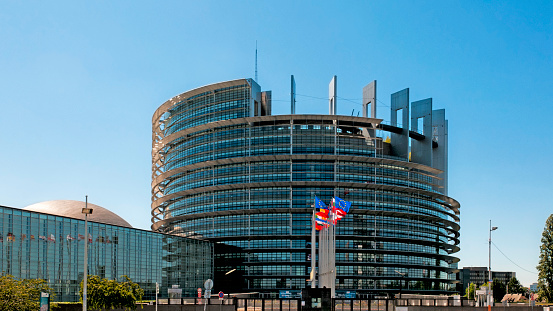 The European Parliament building in Strasbourg, France with flags waving calmly celebrating peace of the Europe. Picture 16/9 .  July 12, 2020.