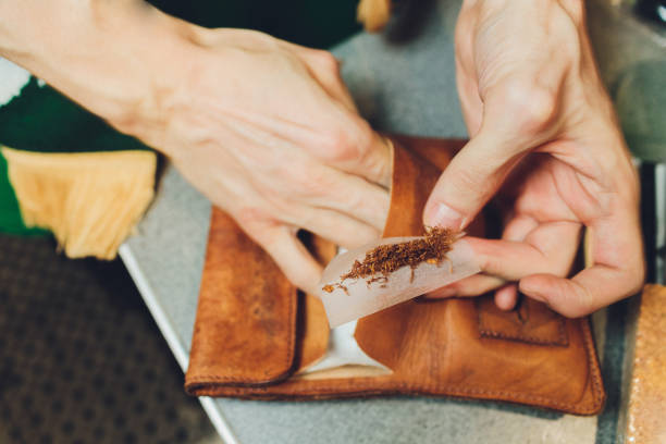 extremely close-up view of a man hands putting a tobacco in a tobacco machine. - tobacco cigarette tobacco product rolling imagens e fotografias de stock